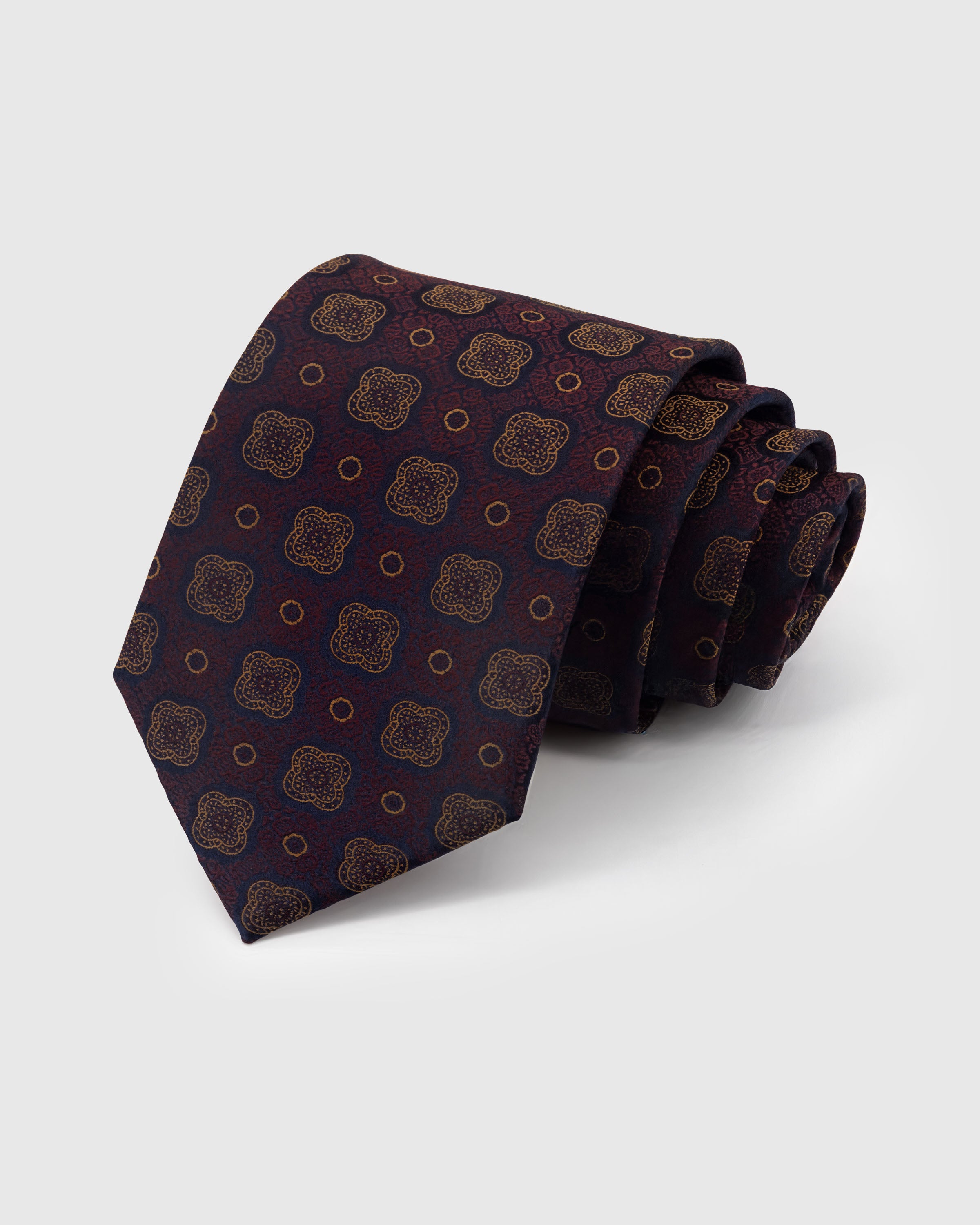 STICKYZOO Claret Quatrefoil Tie in hand-embroidered mulberry silk with amber quatrefoil medallions on claret ground, 45° bias-cut Italian method