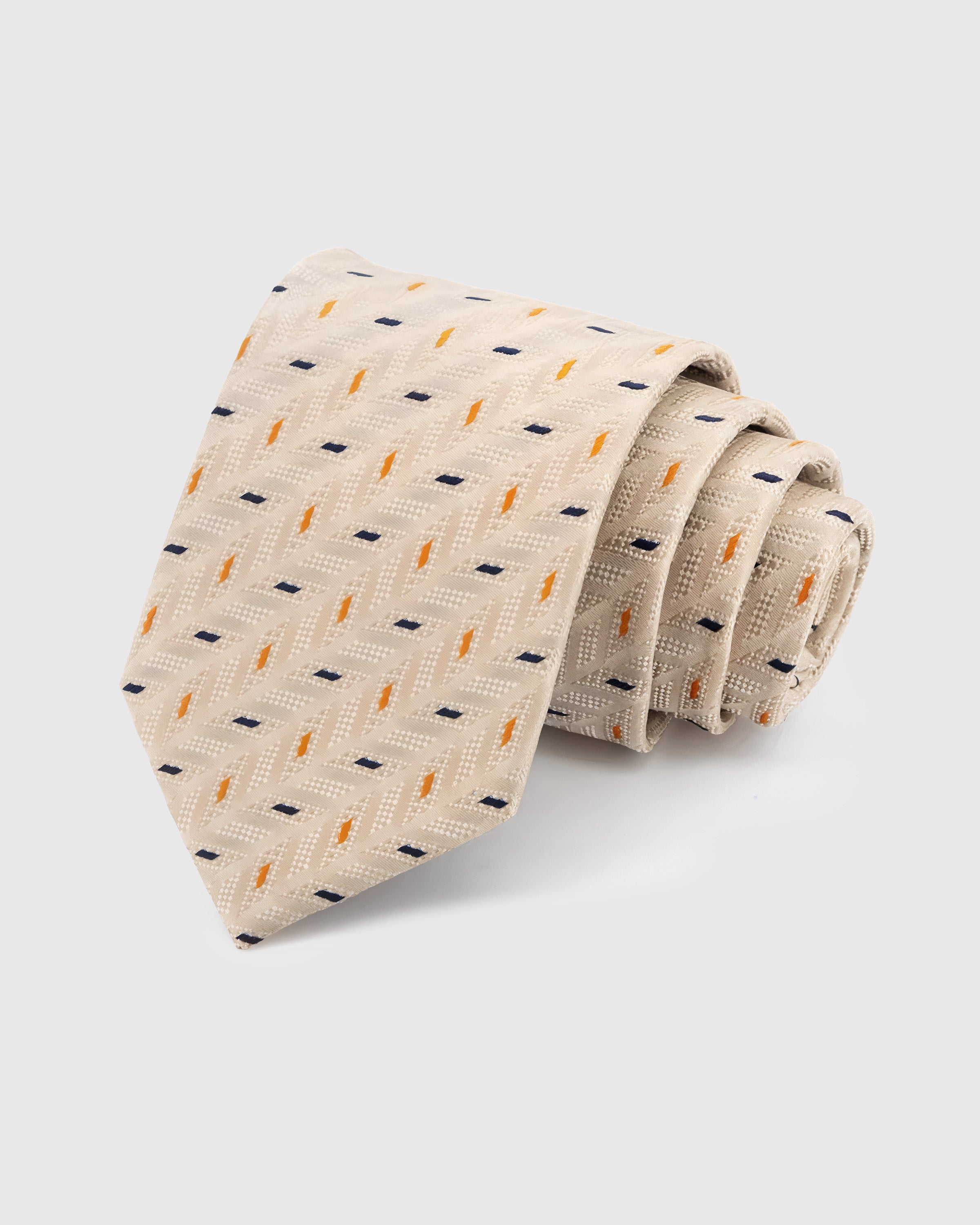 STICKYZOO Pearl Confetti Tie in hand-embroidered mulberry silk with navy and amber confetti dash motifs on warm beige herringbone, 45° bias-cut