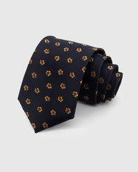 STICKYZOO NAVY HIBISCUS TIE — 100% mulberry silk with hand-embroidered golden amber hibiscus bloom motifs on deep navy with slubbed texture ground
