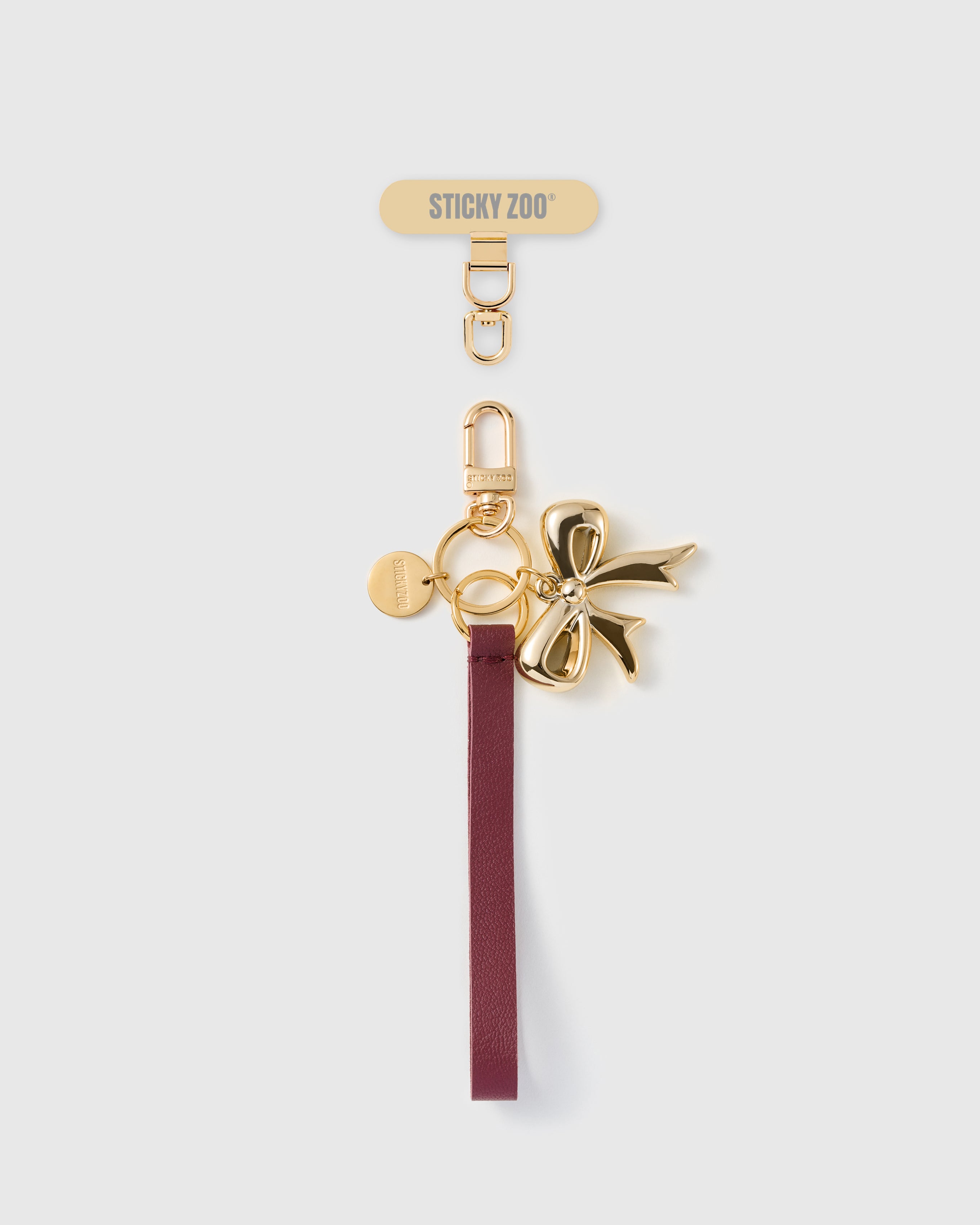 Handmade French Alran wine leather phone strap with polished gold metal bow charm and 18K gold STICKYZOO hardware