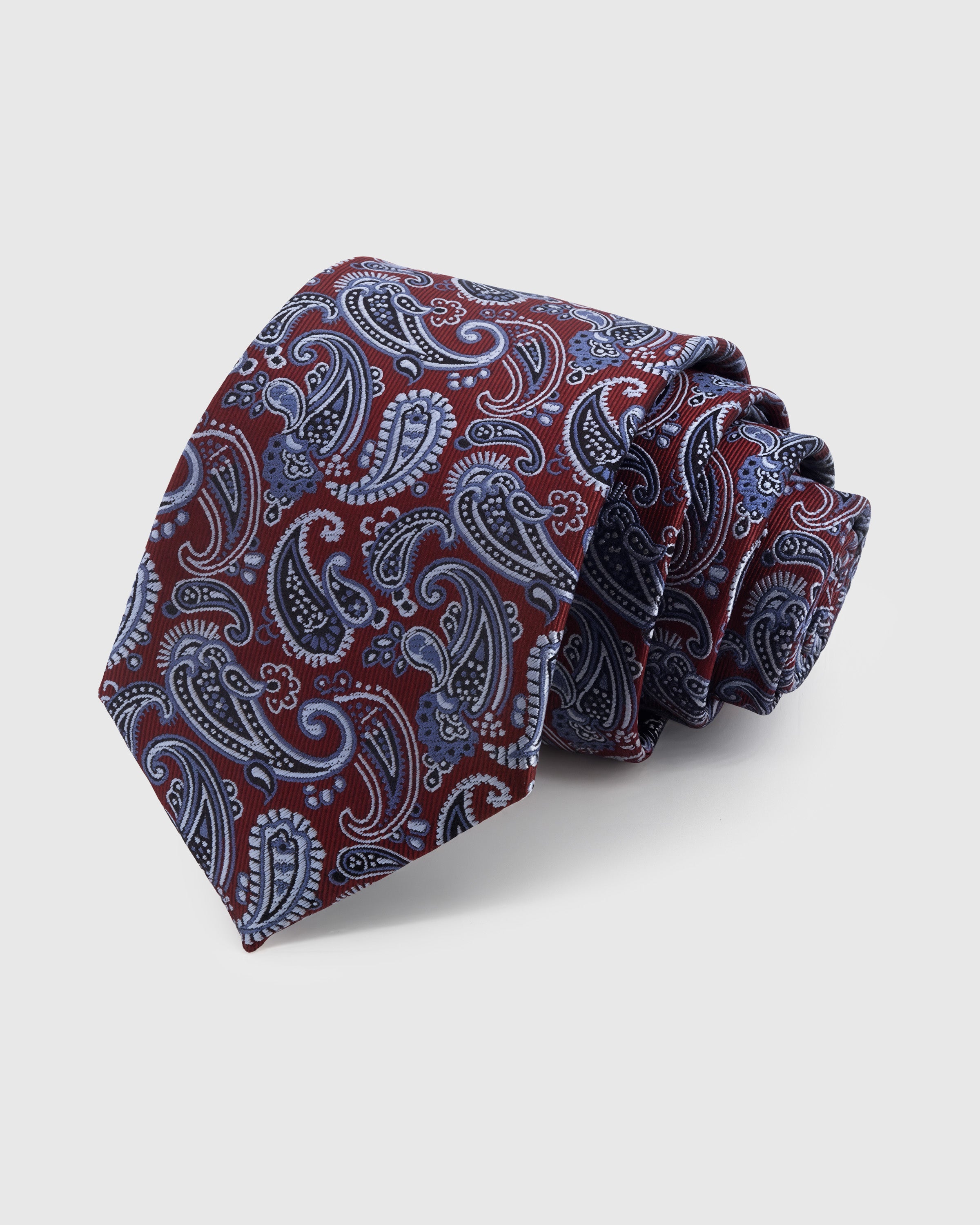 CRIMSON PAISLEY TIE — Hand-embroidered paisley detail on 100% mulberry silk in crimson, showing embroidery texture and silk sheen