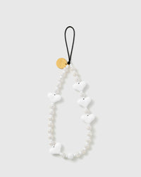 STICKYZOO Snow Heart phone strap laid flat, glossy white puffy heart beads and ribbed cream-white disc beads on a black stretch-cord loop with a gold-tone disc.