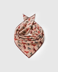 Silk horse-print scarf coiled to show the soft drape and the burgundy border catching light