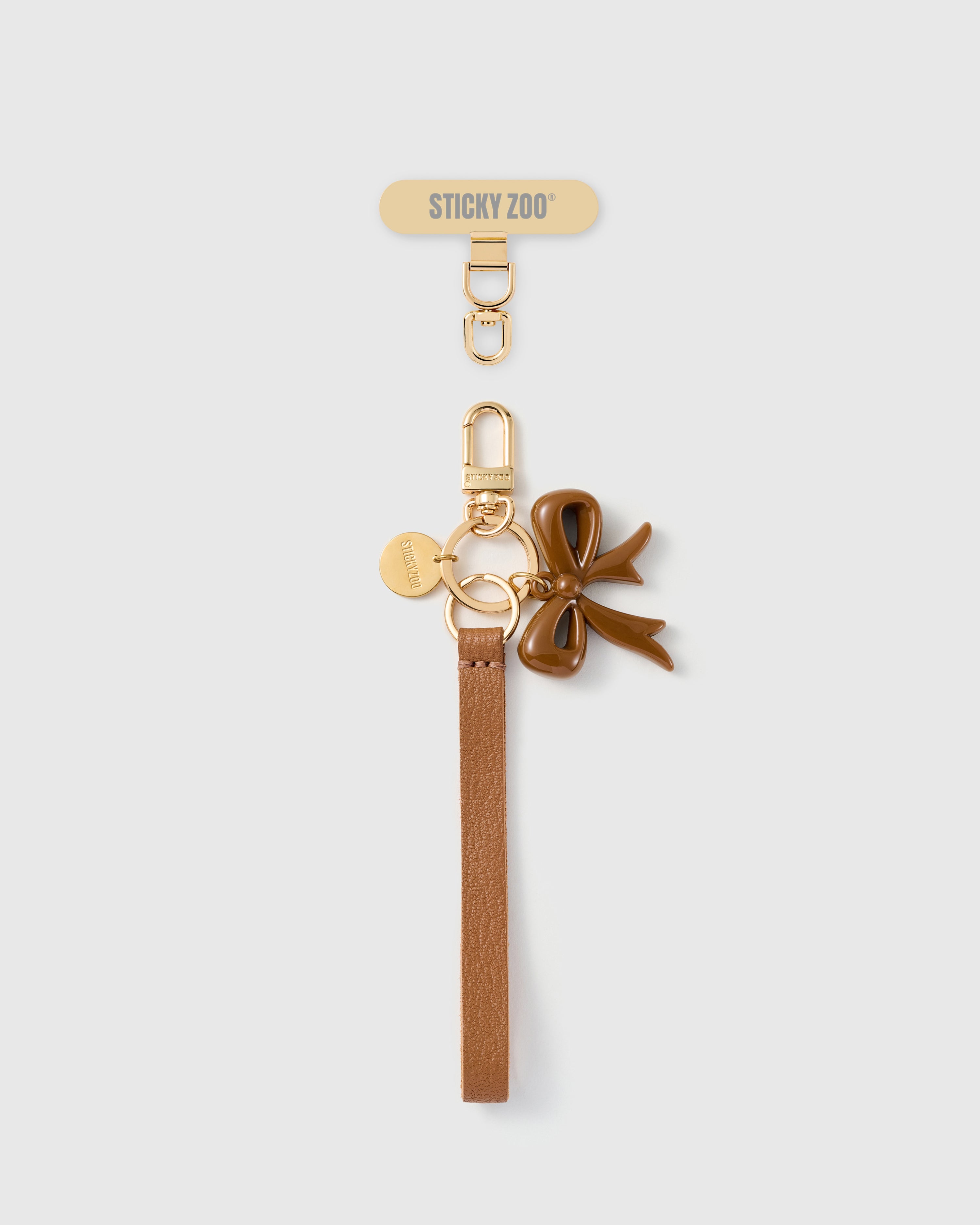 Handmade French Alran hazel tan leather phone strap with glossy cocoa enamel bow charm and 18K gold STICKYZOO hardware