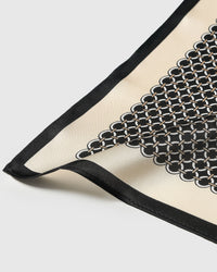 Silk chain link scarf coiled through a leather ring showing the ivory grid on black