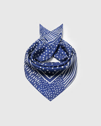 Cobalt silk scarf coiled to show the small-dot center field framed by an ivory line border