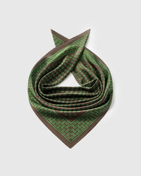 Silk stirrup scarf coiled to show the soft drape and the green grid-framed border across pure silk