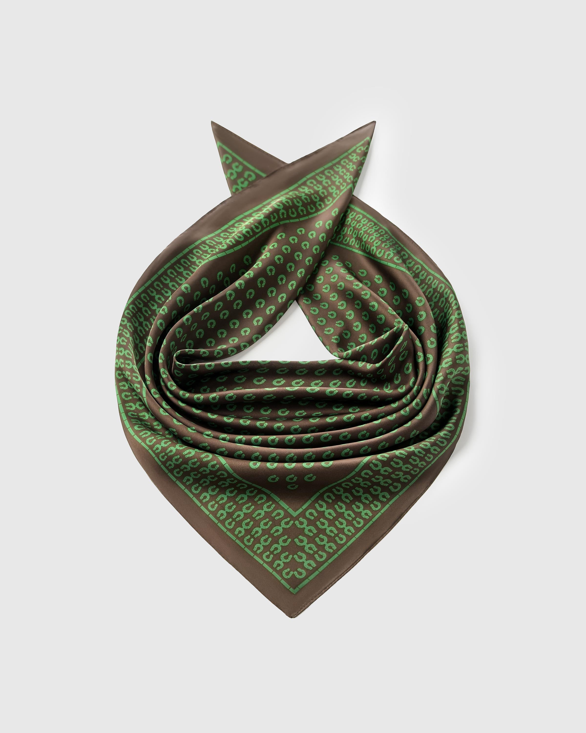 Silk stirrup scarf coiled to show the soft drape and the green grid-framed border across pure silk