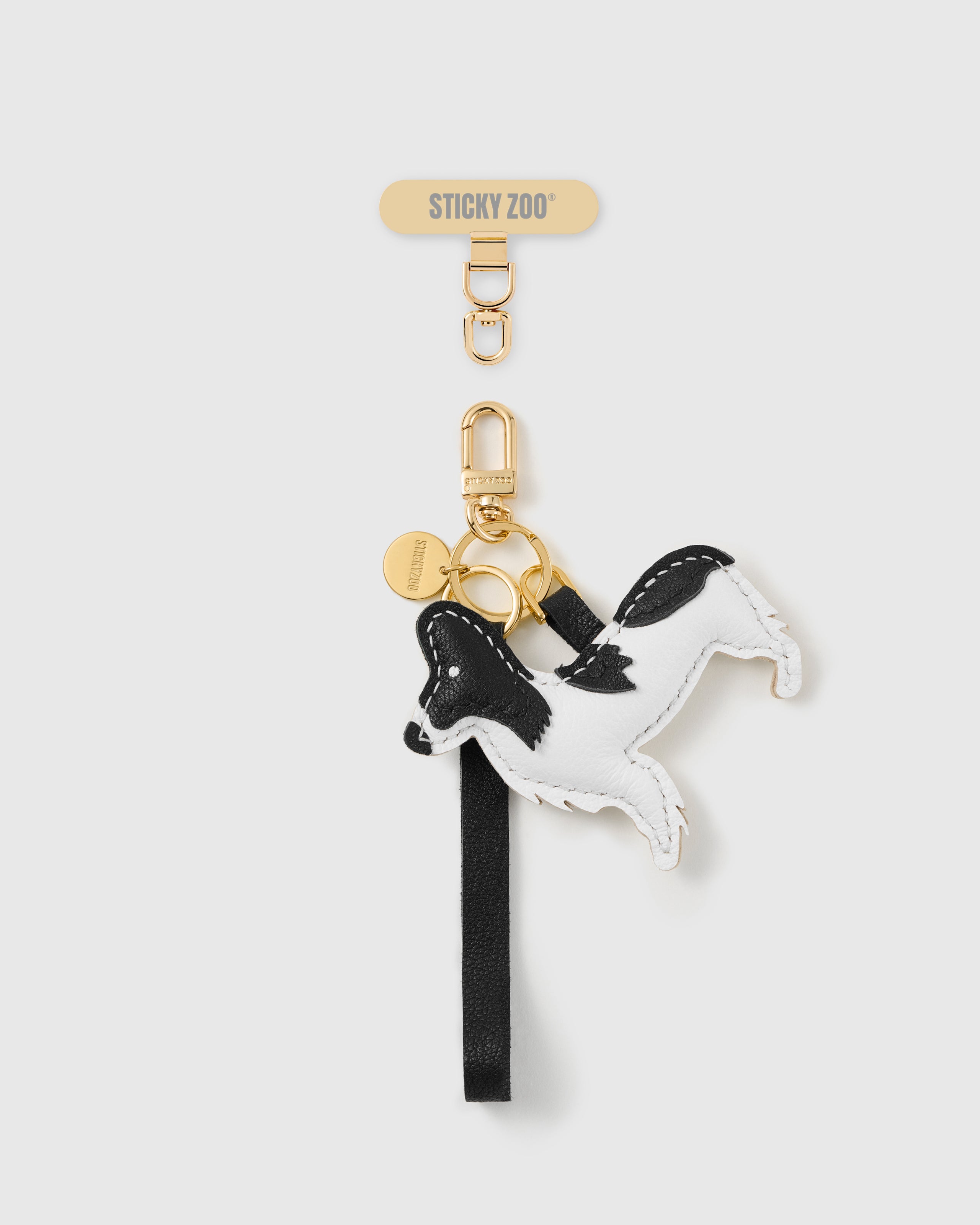 STICKYZOO noir patch pup leather phone strap, hand-stitched black-and-white leather dog charm on a black strap
