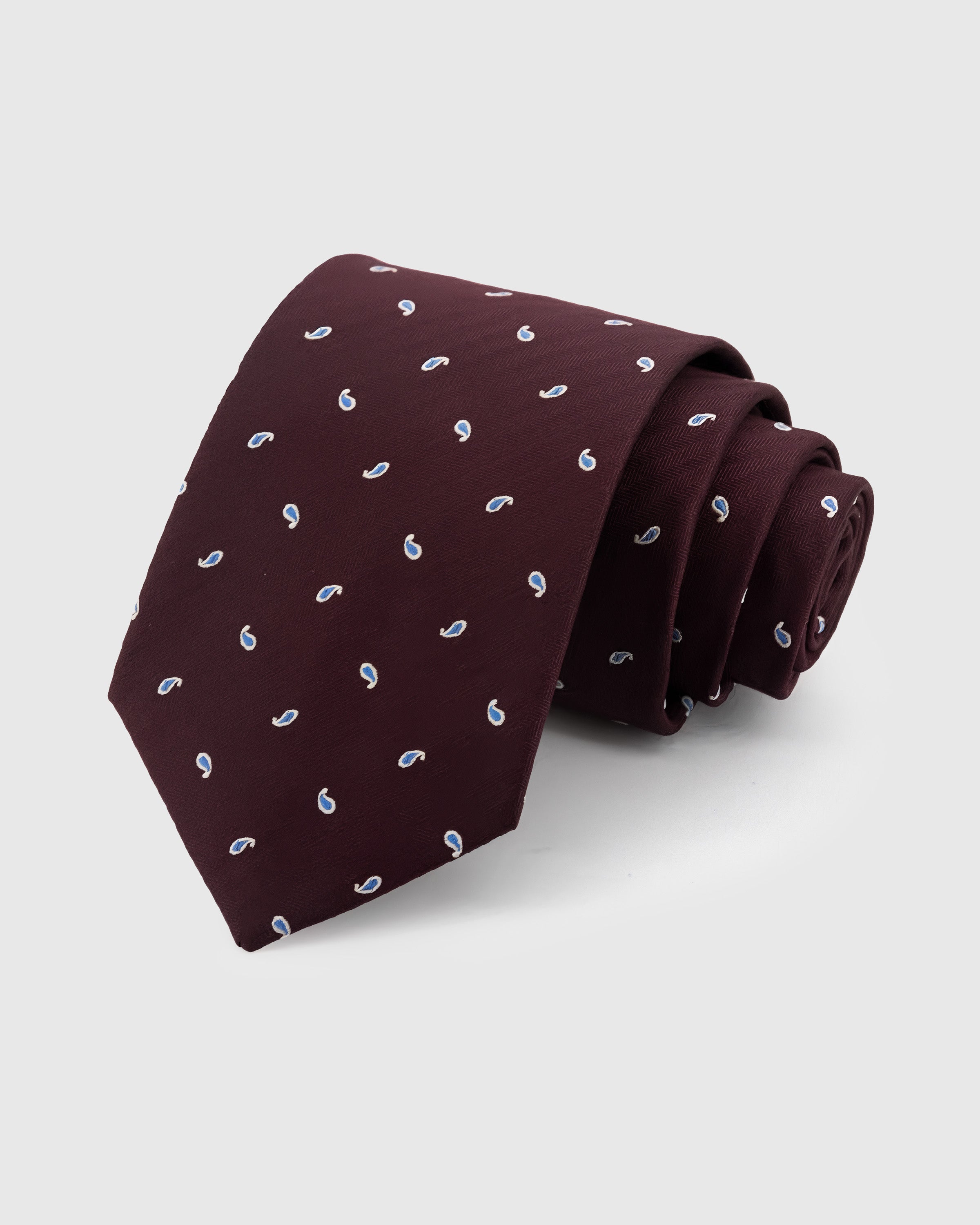 STICKYZOO Burgundy Paisley Drop Tie in hand-embroidered mulberry silk with blue paisley motifs on herringbone ground, 45° bias-cut