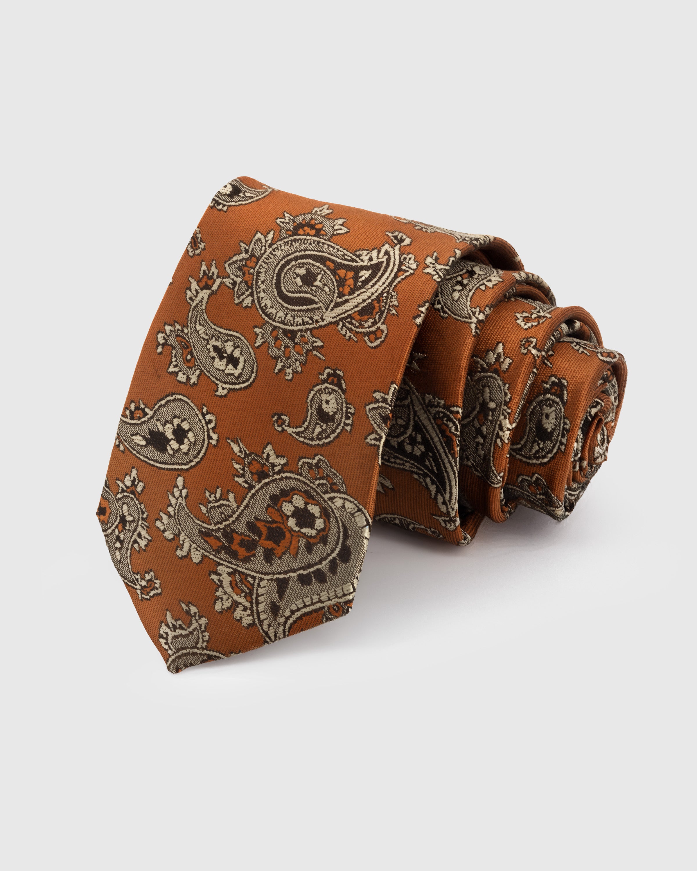 AMBER PAISLEY TIE — Hand-embroidered paisley detail on 100% mulberry silk in amber, showing embroidery texture and silk sheen