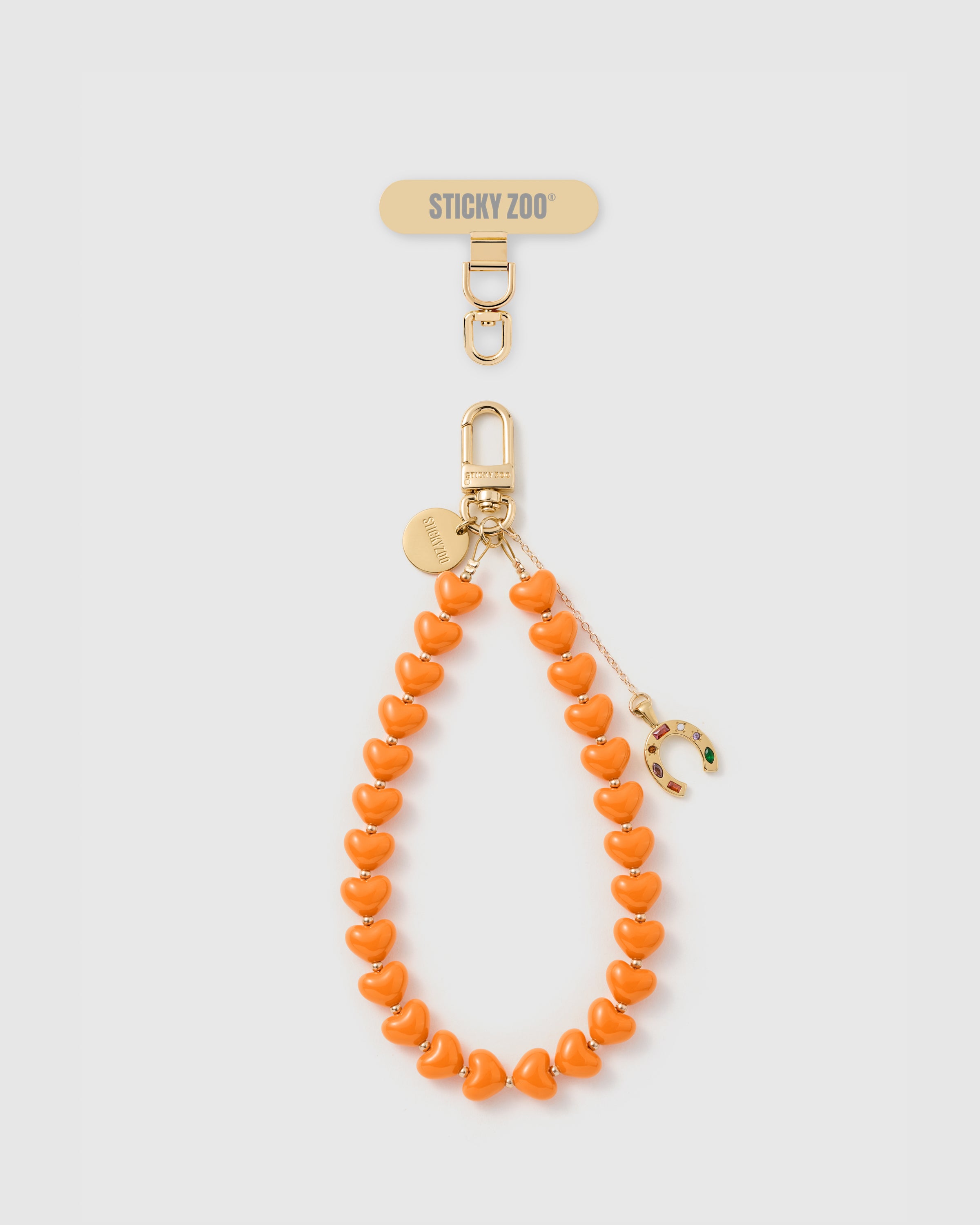 {Good-luck horseshoe} Jeweled gold horseshoe charm on tangerine heart-bead phone strap with STICKYZOO engraved disc