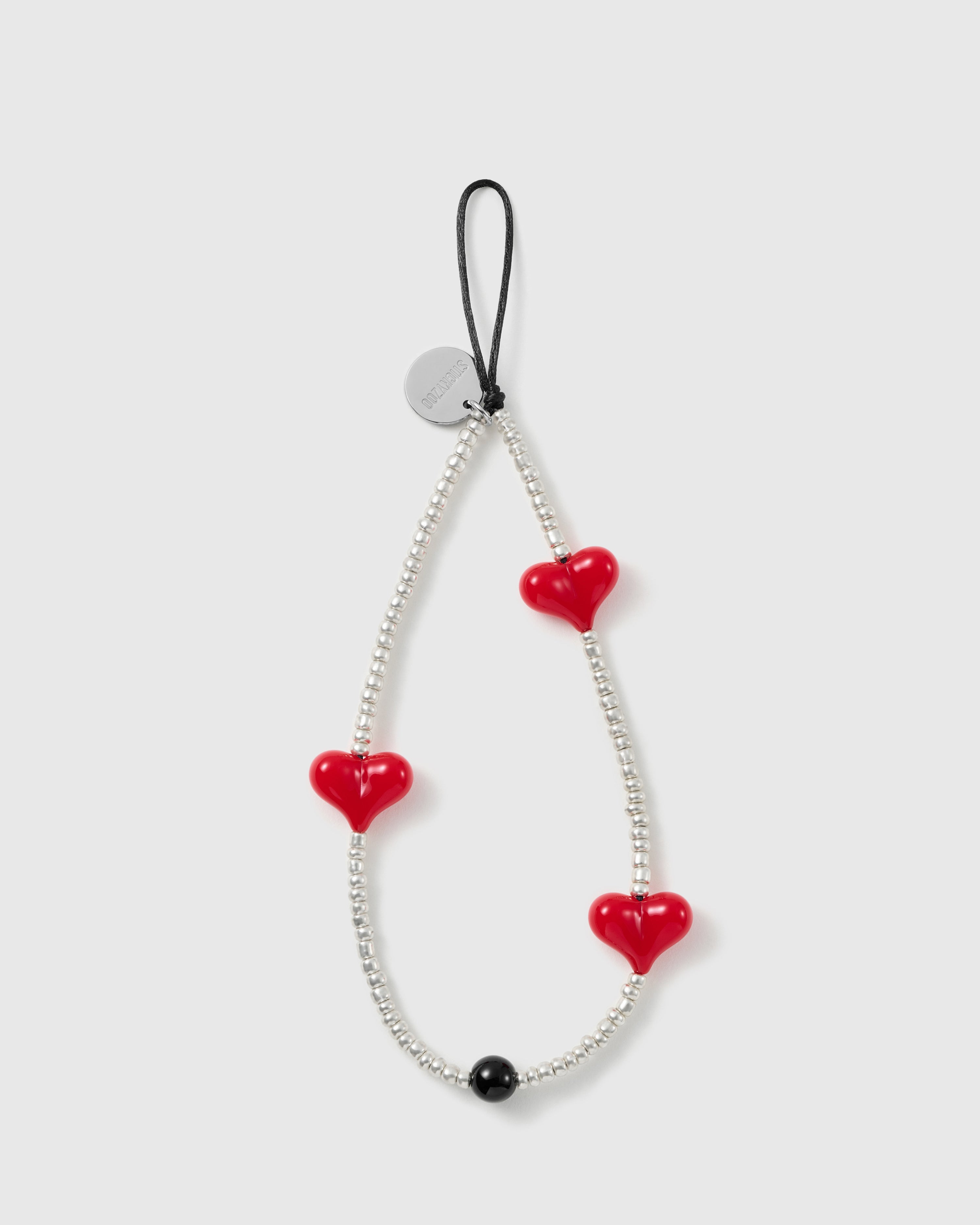 STICKYZOO beaded phone strap laid flat, a full loop of silver-tone seed beads with three glossy red hearts, one black bead and a silver disc.