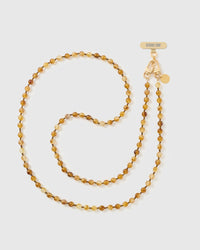 Full-length STICKYZOO crossbody phone strap of translucent amber and honey resin beads with bronze spacers, coiled beside a gold-tone dual clasp.