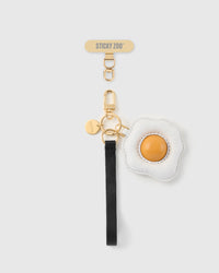 STICKYZOO sunny egg leather phone strap — puffed white leather fried egg with golden yolk, black Alran strap, gold hardware