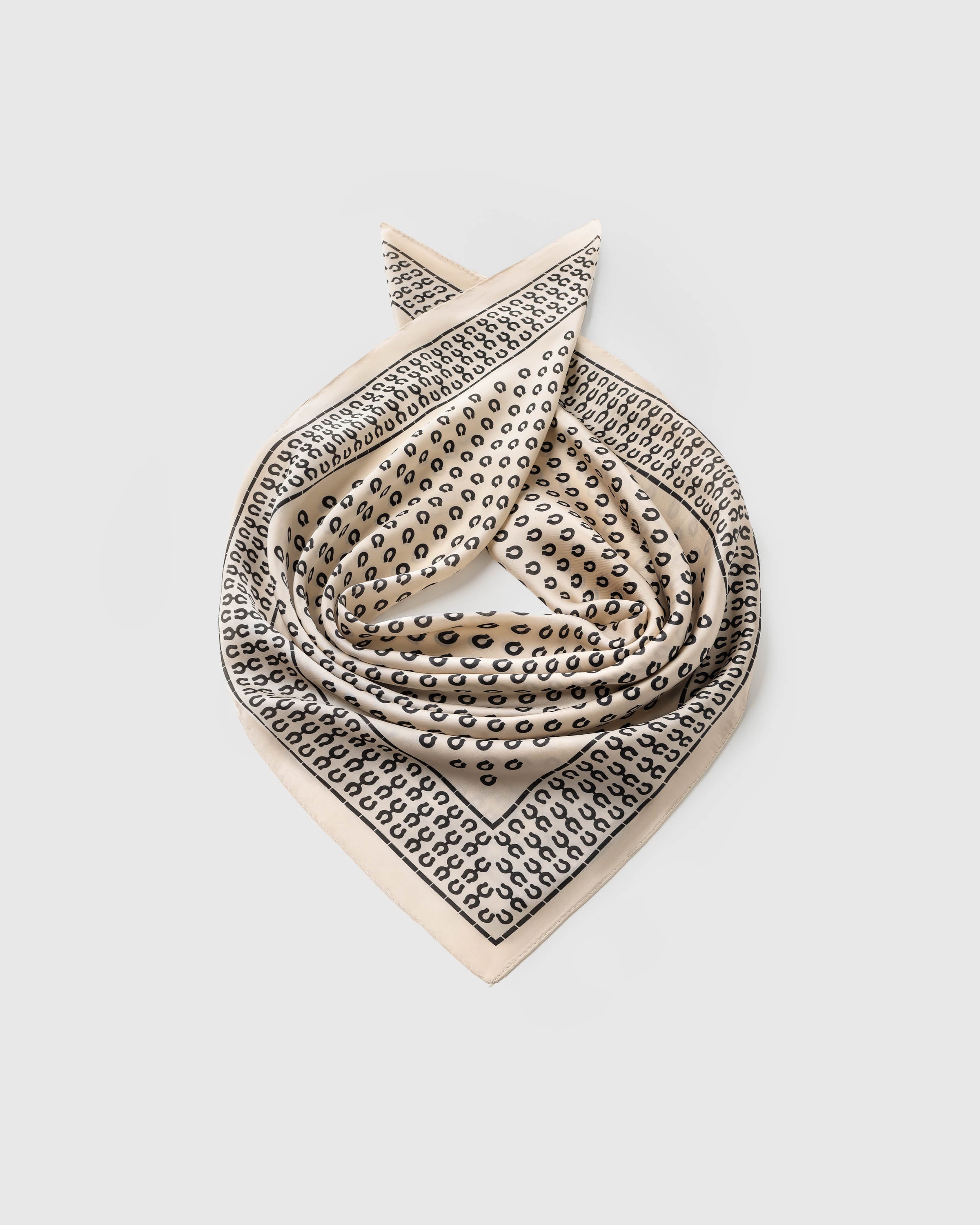 Silk horseshoe scarf coiled to show the soft drape and the grid-framed border on small-square format