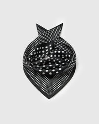 Black silk polka dot scarf coiled into a soft bandana fold showing both dot scales