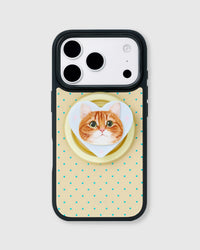 Cream phone case with teal polka dots and a heart-shaped MagSafe grip framing a ginger tabby cat portrait by STICKYZOO