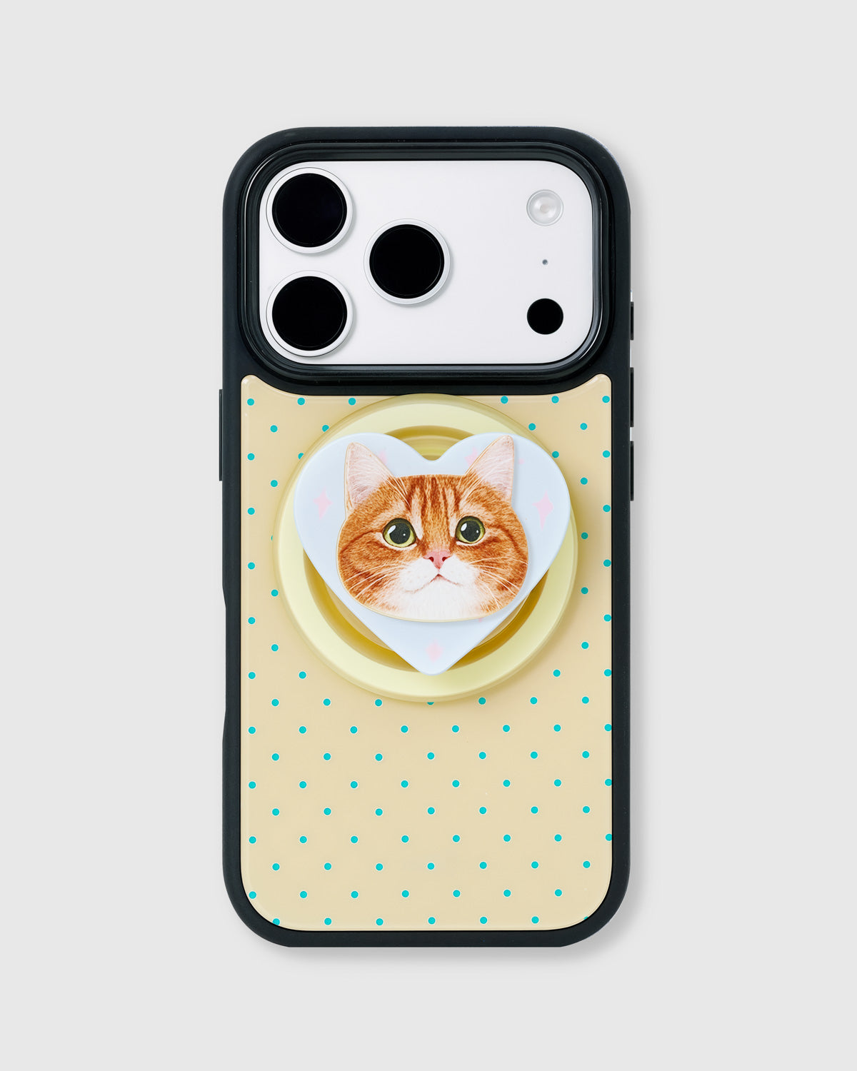Cream phone case with teal polka dots and a heart-shaped MagSafe grip framing a ginger tabby cat portrait by STICKYZOO