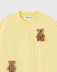 Close-up of dual plush teddy bear appliques on lemon 450gsm cotton fleece showing 3D texture