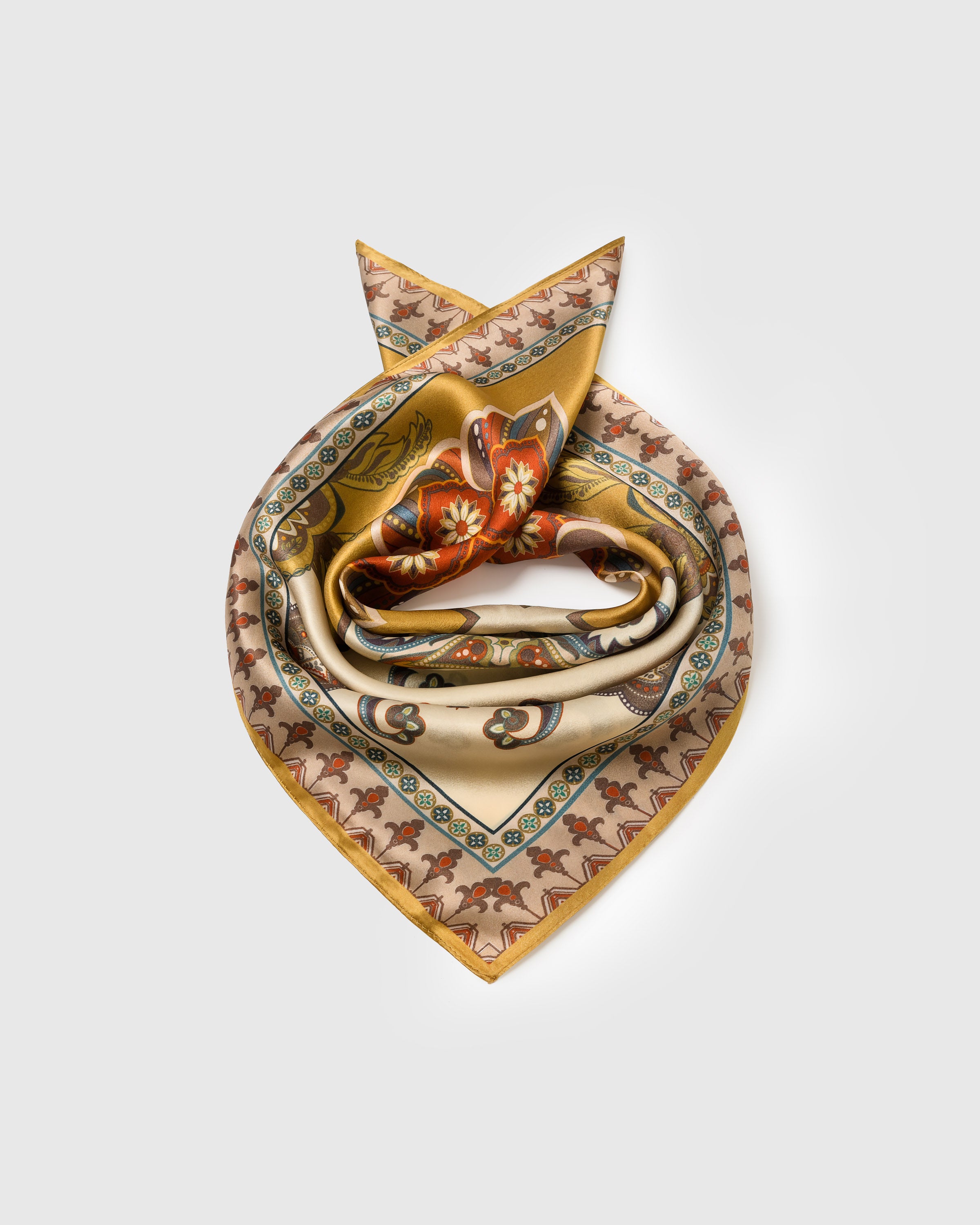 Silk medallion scarf coiled to show the soft drape of pure silk and the saffron field at the edges