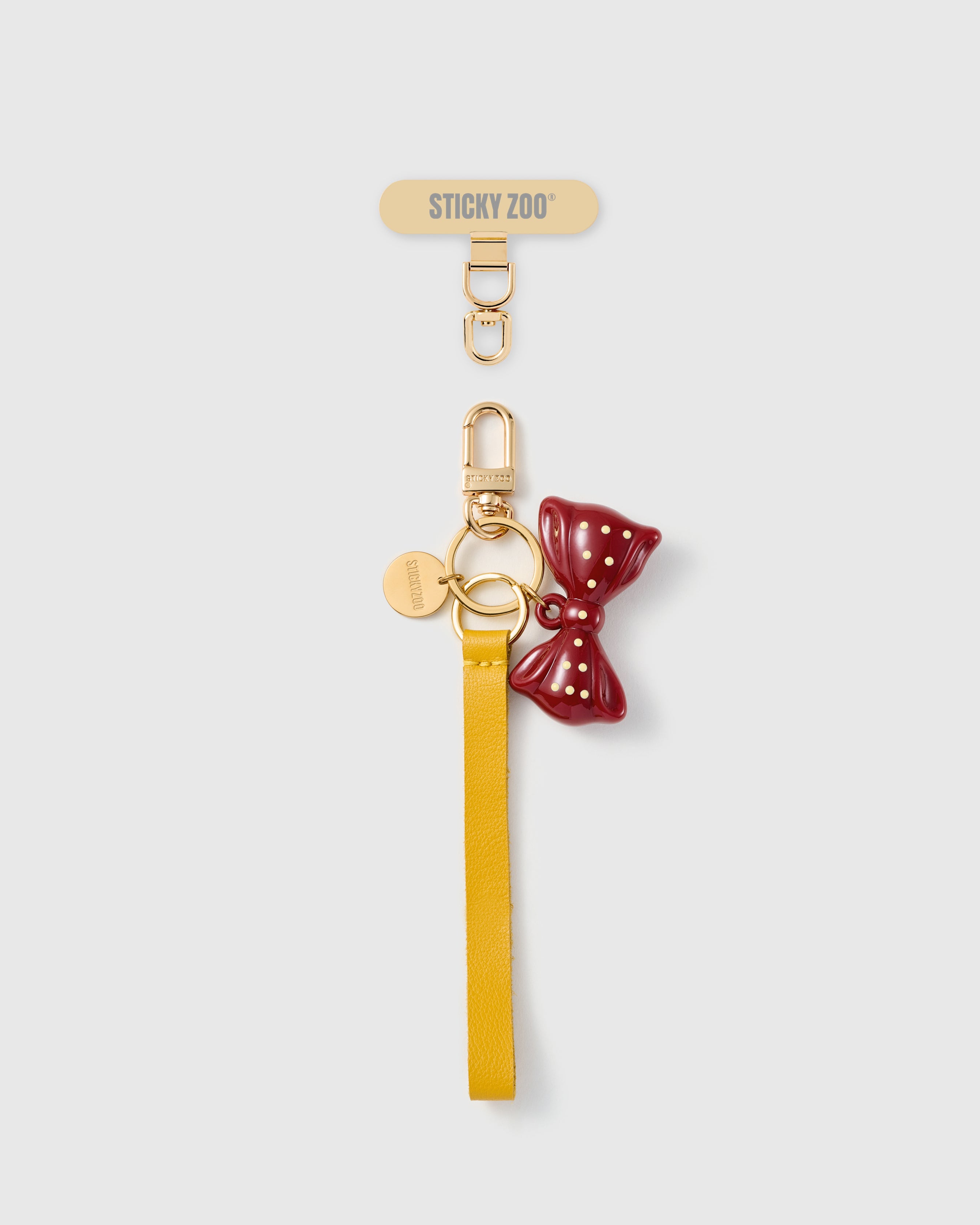 Handmade French Alran saffron yellow leather phone strap with burgundy and gold polka-dot enamel bow charm and 18K gold STICKYZOO hardware
