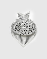 Ivory silk polka dot scarf coiled into a soft bandana fold showing both dot scales across the field