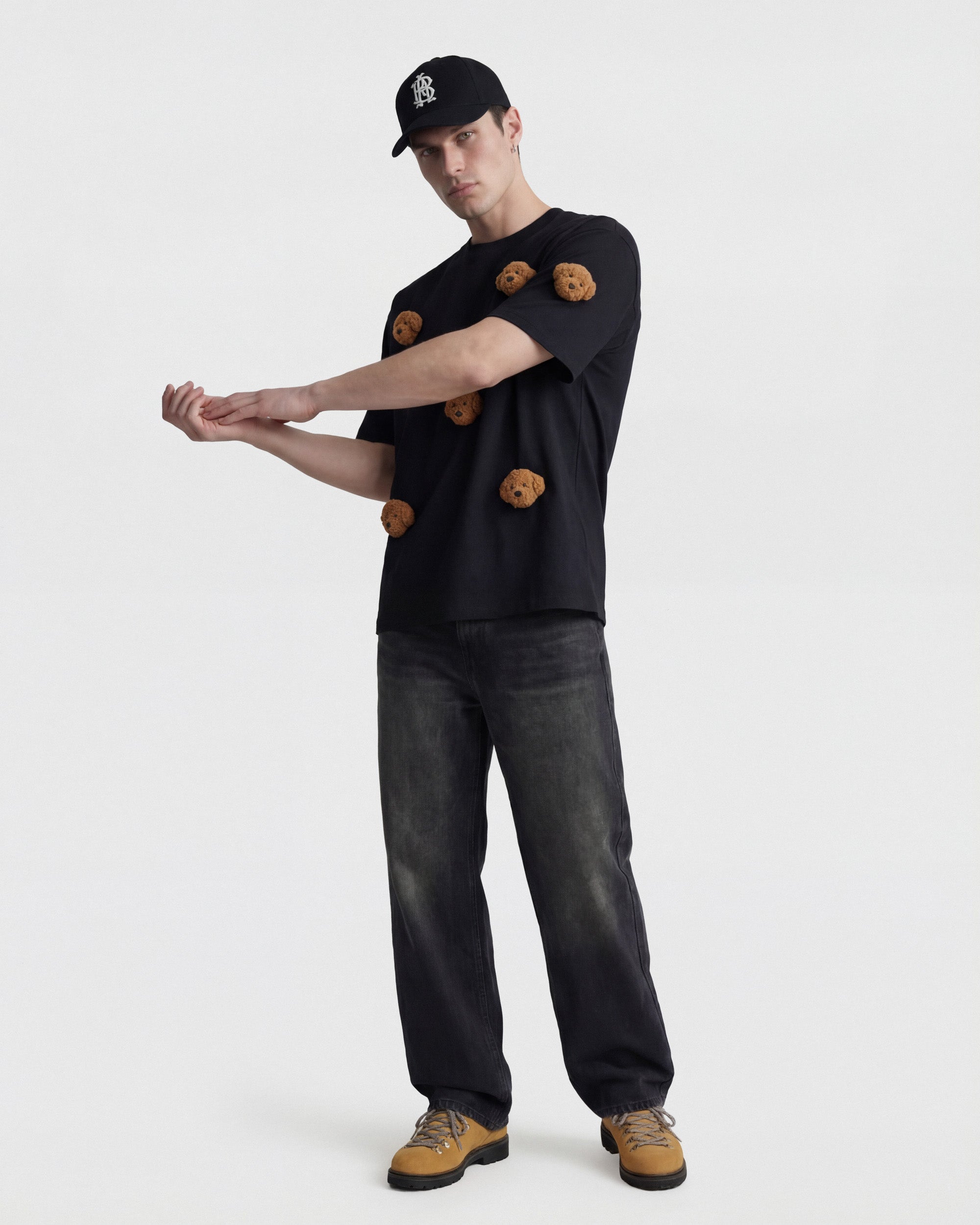 {{Not printed — stitched}} Model in black Poodle Parade T-Shirt angled pose showing plush poodle appliques