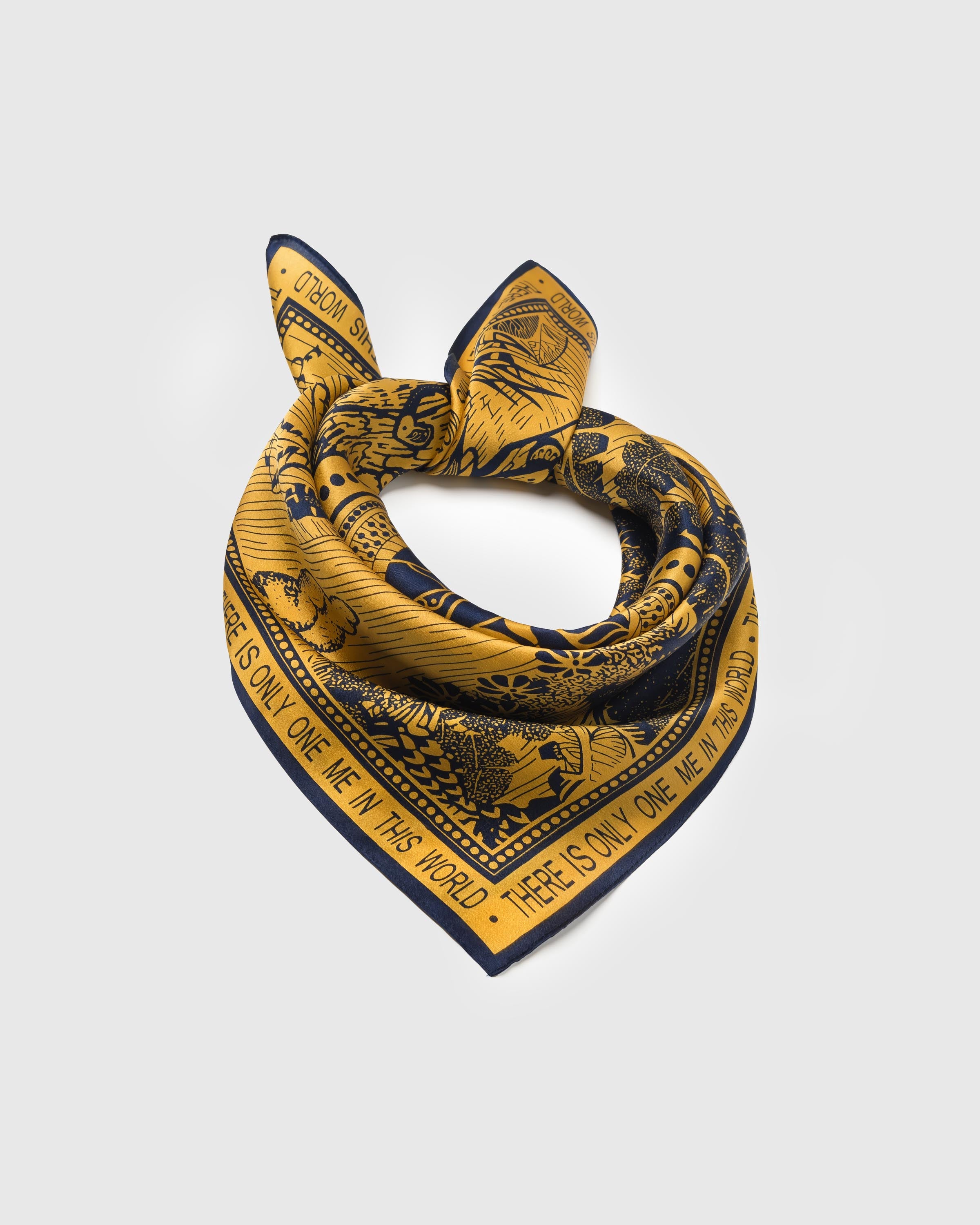 Saffron paradise silk scarf coiled into a ring showing the soft drape and the navy block-text border