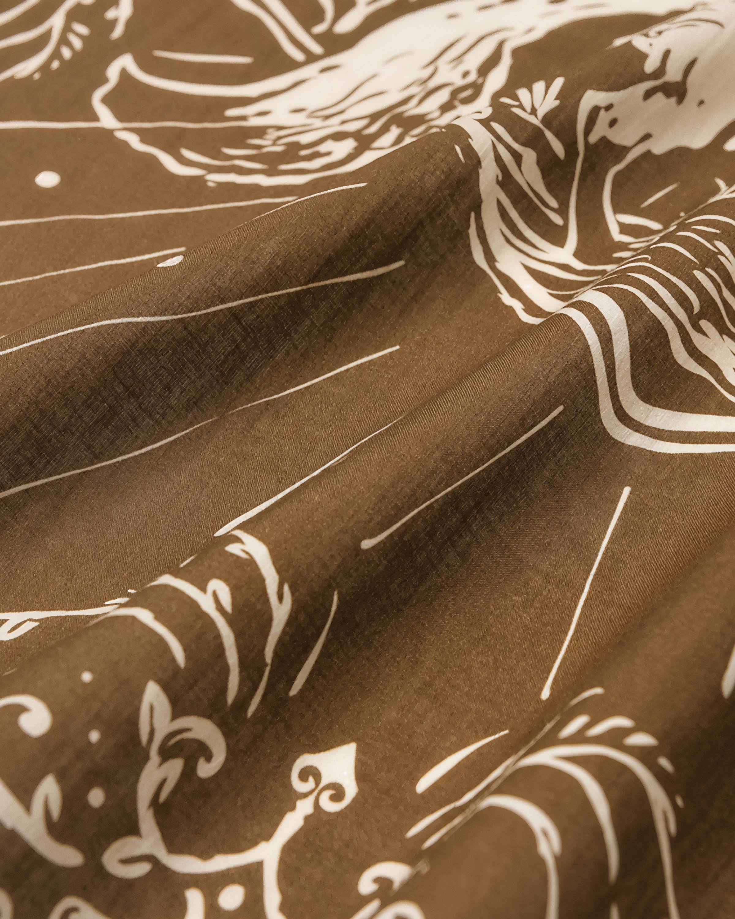 Detail of the hand-illustrated fox under a crescent moon printed in ivory ink on the olive silk
```