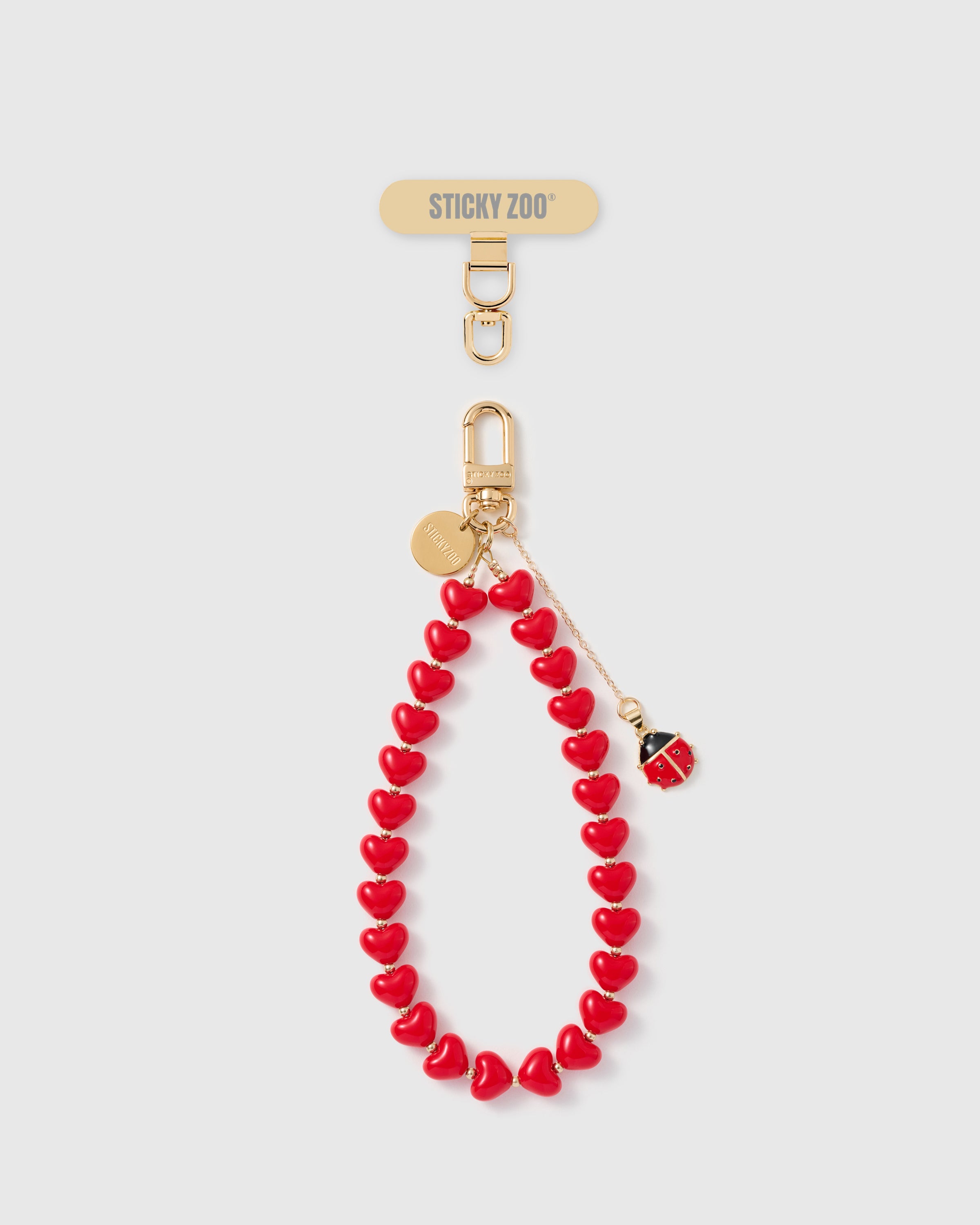 Lucky ladybug charm phone strap with crimson heart beads and gold hardware by STICKYZOO