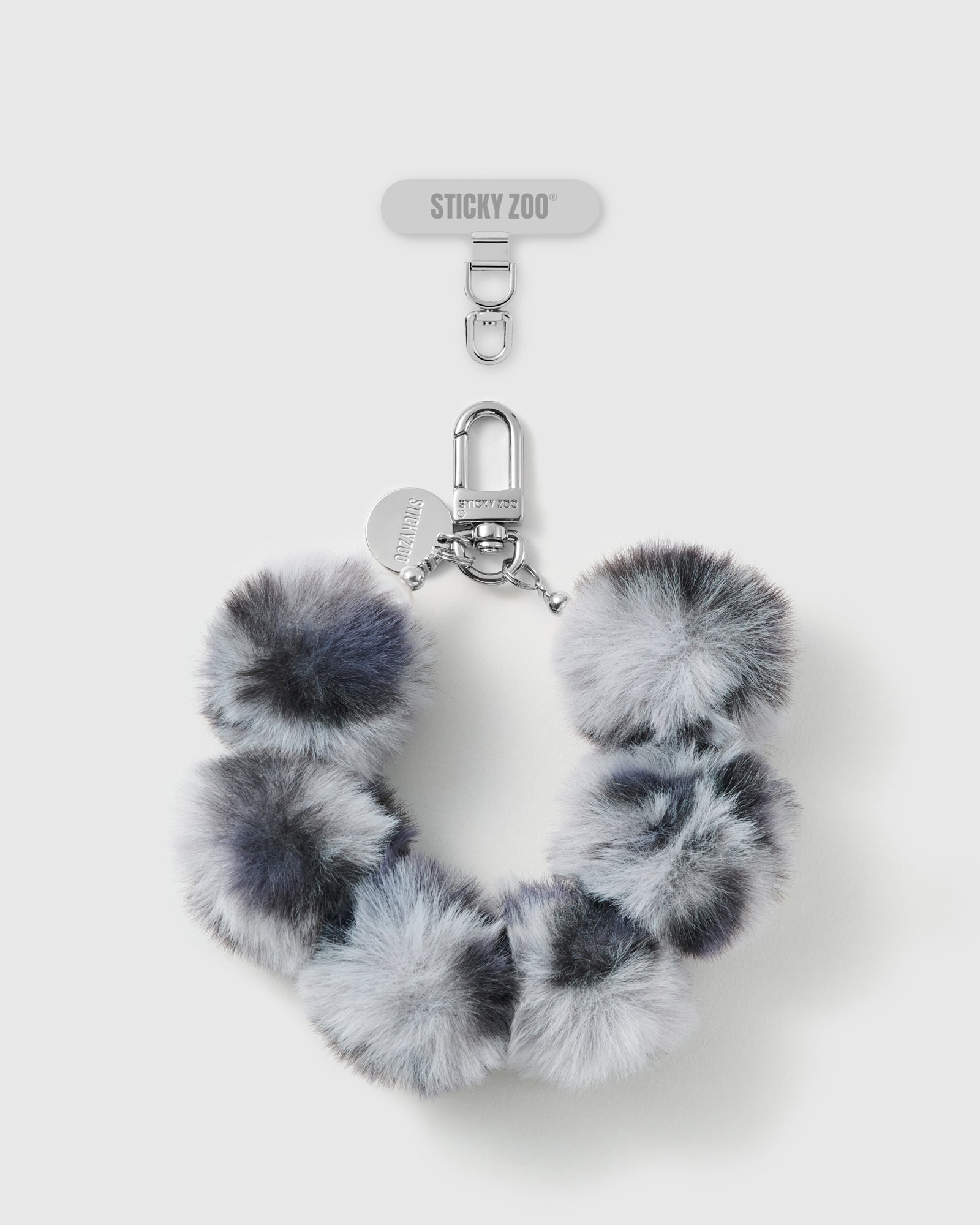 Handmade smoke grey faux-fur pom phone strap by STICKYZOO with silver-tone engraved hardware, shown with the Phone Strap Card
