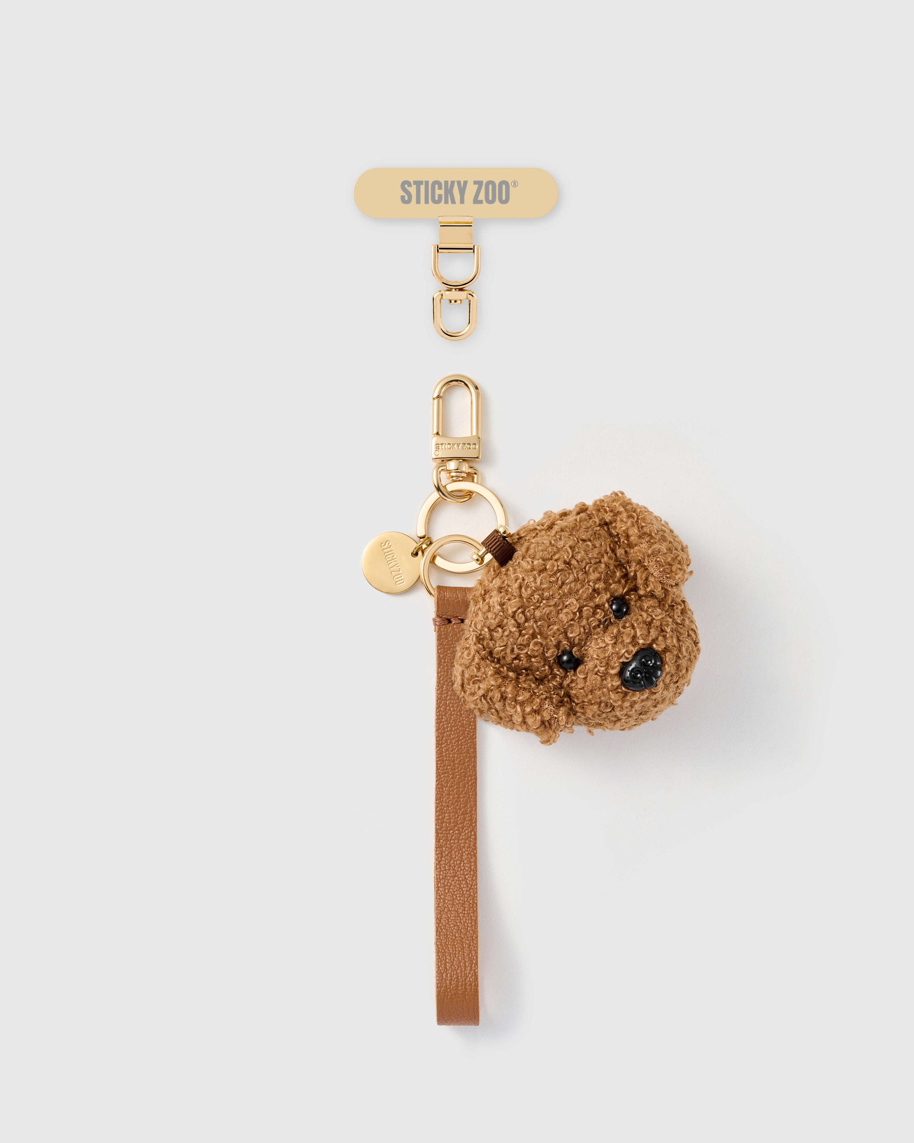 Handmade French Alran cocoa tan leather phone strap with plush brown teddy-face charm and 18K gold STICKYZOO hardware