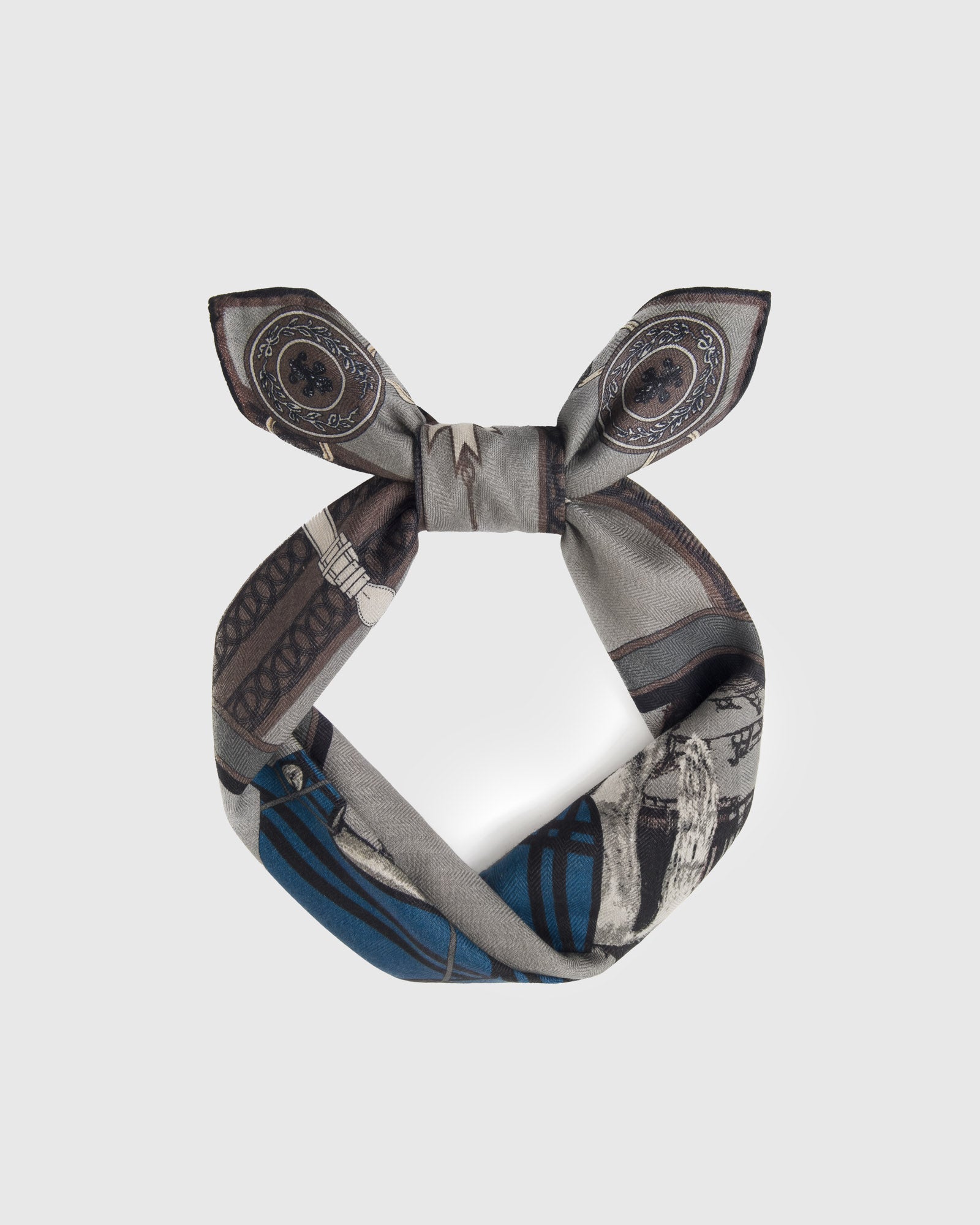 Silk equestrian scarf coiled through a leather ring showing the cobalt and grey palette
