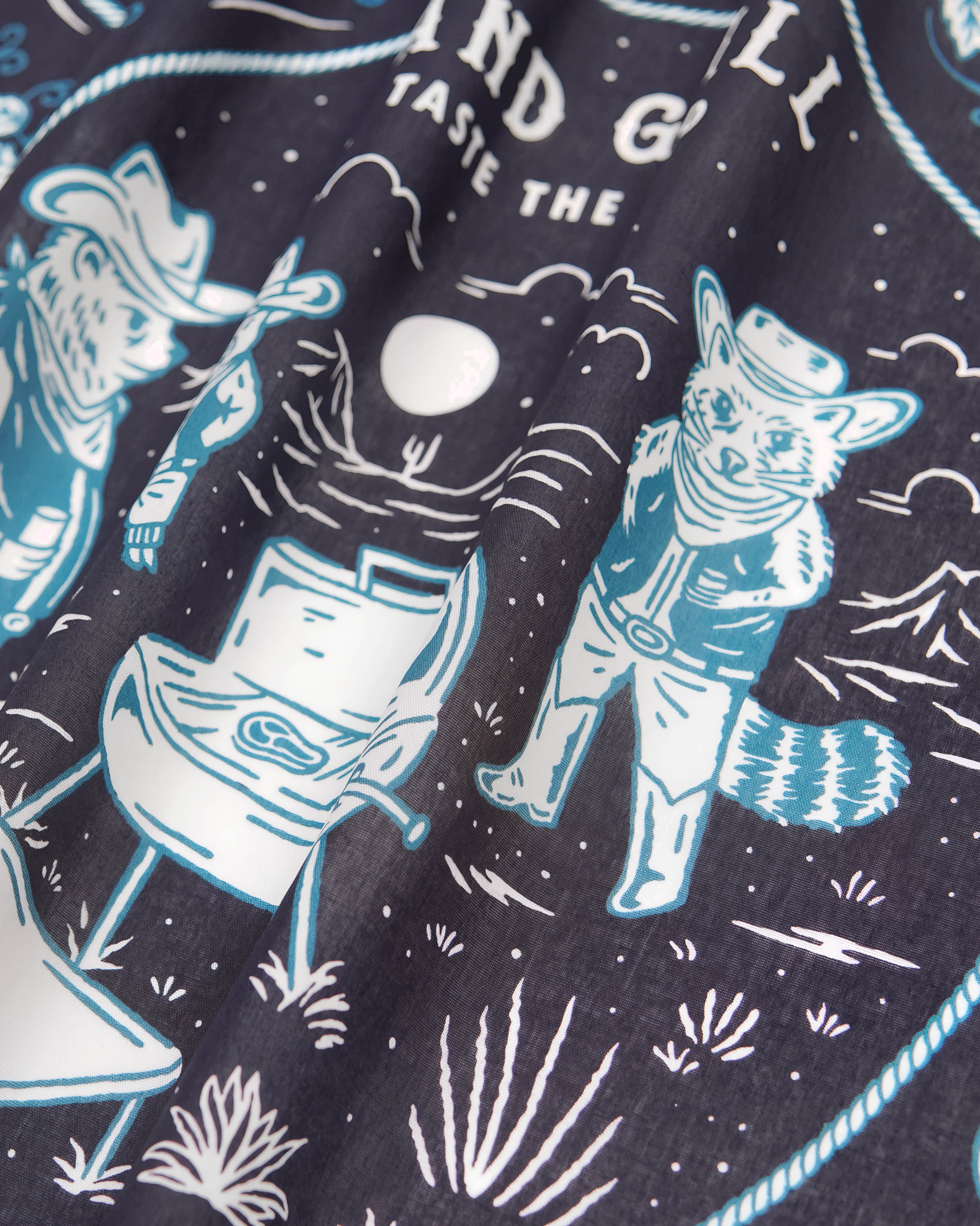 Detail of the printed campfire scene with the fox, bear, and raccoon inked in ivory and teal on midnight silk
```