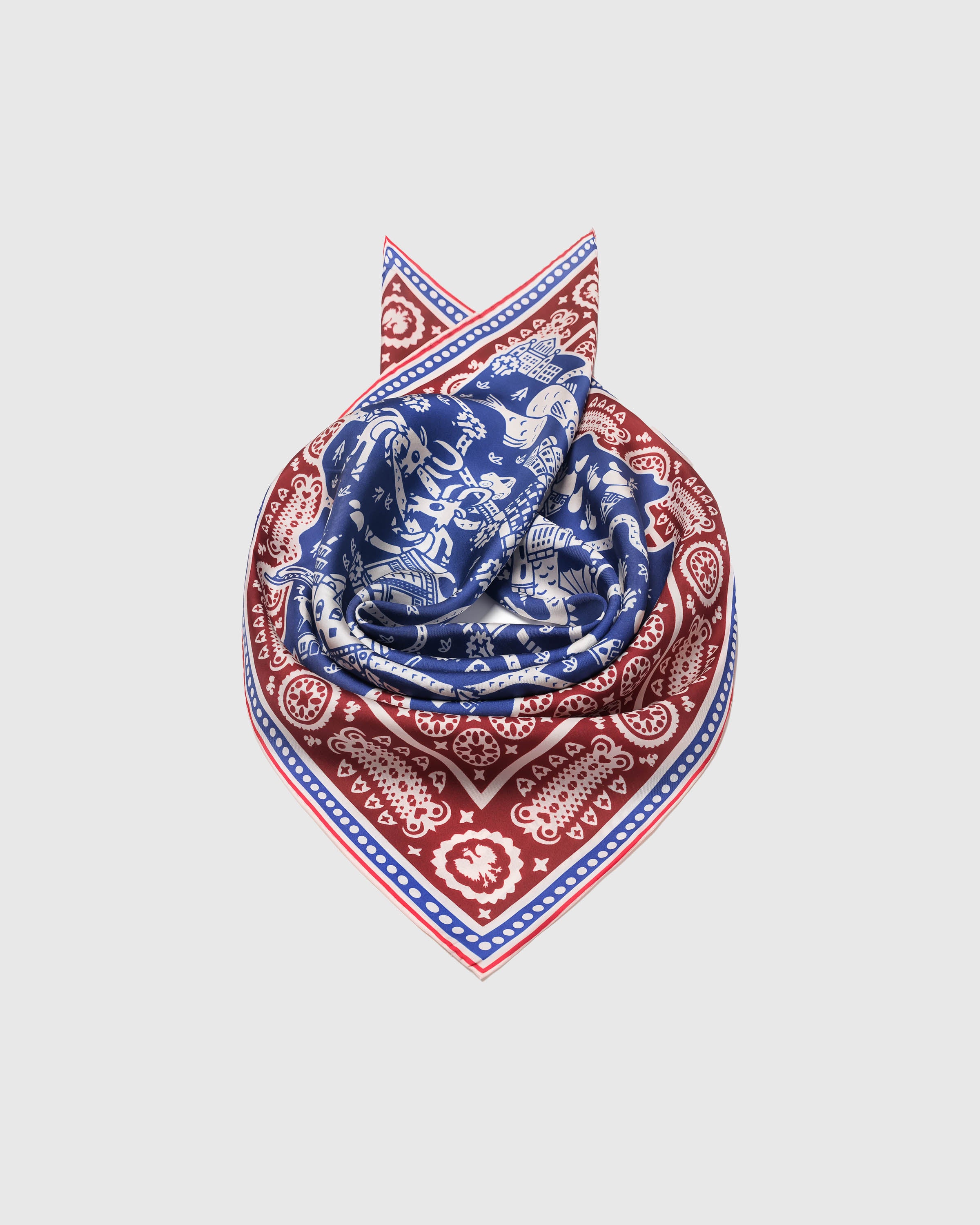 Cobalt and burgundy silk scarf coiled to show the burgundy paisley border wrapping the fold