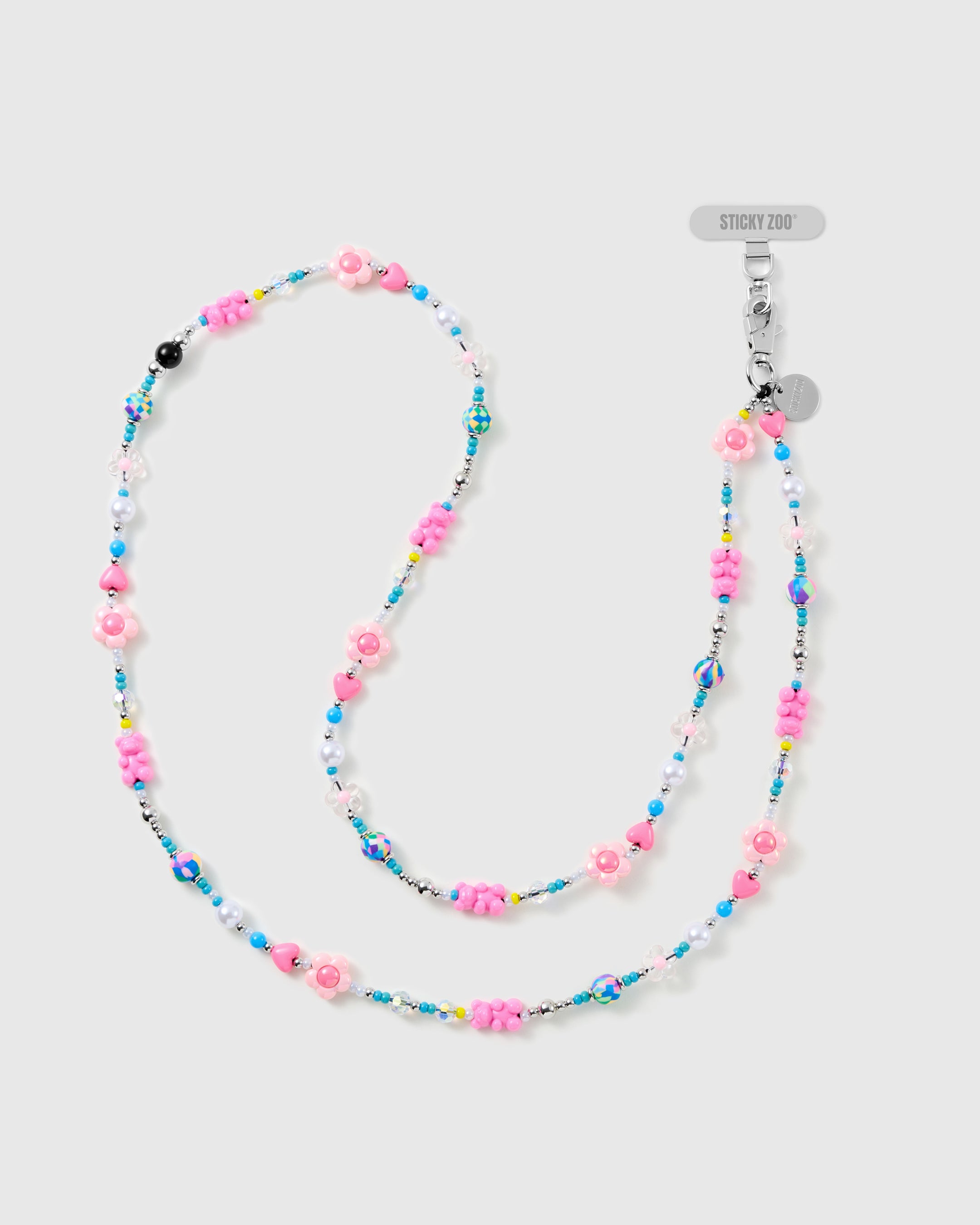 STICKYZOO cross-body phone strap laid in an S-curve, strung with pink flower beads, hearts, faux-pearl and turquoise beads, silver-tone tag and clasp.