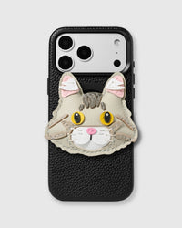 STICKYZOO Maine Coon Cat Charm Case — handmade 3D leather cat charm with golden eyes, tabby markings, and pink nose on textured black leather phone case. Hand-cut, stitched, and layered from French Alran leather. Rated 4.9★.