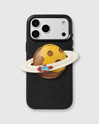 STICKYZOO Saturn Charm Case in black vegan leather with handmade French Alran leather Saturn planet charm featuring hand-cut ring and rocket detail, raised camera bezels, and MagSafe compatible design.