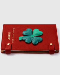 Four-leaf clover charm detail showing hand-layered green leather petals with stem on STICKYZOO A5 notebook