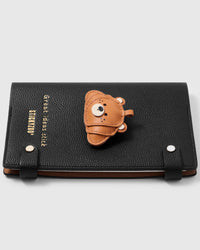 French Alran leather bear peeking over a croissant on STICKYZOO notebook, hand-cut and stitched with multi-layer construction