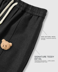 Close-up of 3D plush teddy bear face applique on black wool-blend fabric showing stuffed dimensional detail