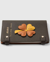 French Alran leather lucky clover charm detail showing hand-cut and hand-stitched leather layers on STICKYZOO notebook