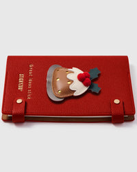 Christmas pudding charm detail showing hand-layered brown leather dome, white icing, holly leaves, and red berries on STICKYZOO A5 notebook