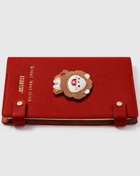 Lion amulett charm detail showing hand-layered brown leather mane, white face, and apple on STICKYZOO A5 notebook