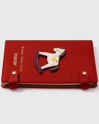 Rocking horse charm detail showing hand-layered white and gold leather with dark rockers on STICKYZOO A5 notebook