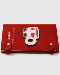 Coffee cup charm detail showing hand-layered white leather body with red heart eyes and brown wheels on STICKYZOO A5 notebook