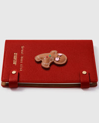Gingerbread doll charm detail showing hand-layered brown leather with icing stitches and button details on STICKYZOO A5 notebook
