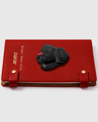 Black poodle charm detail showing layered curly leather texture and hand-stitched features with pink tongue on STICKYZOO notebook
