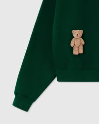 Front view of forest green Saint Teddy Bear Sweatshirt showing plush bears and ribbed details
